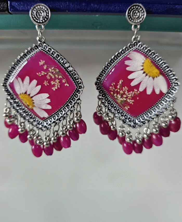 Pink resin earrings featuring daisies and purple bead detailing