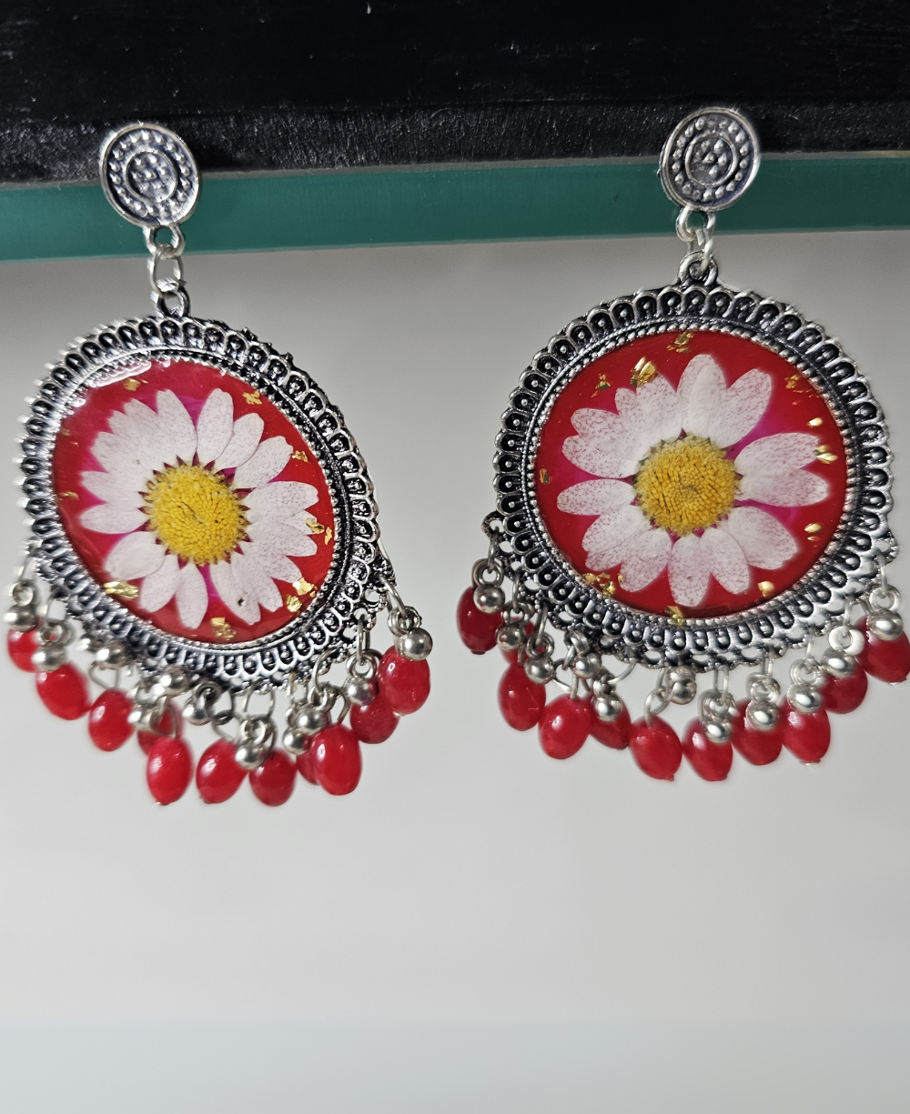 Red resin earrings with white daisies and red bead accents