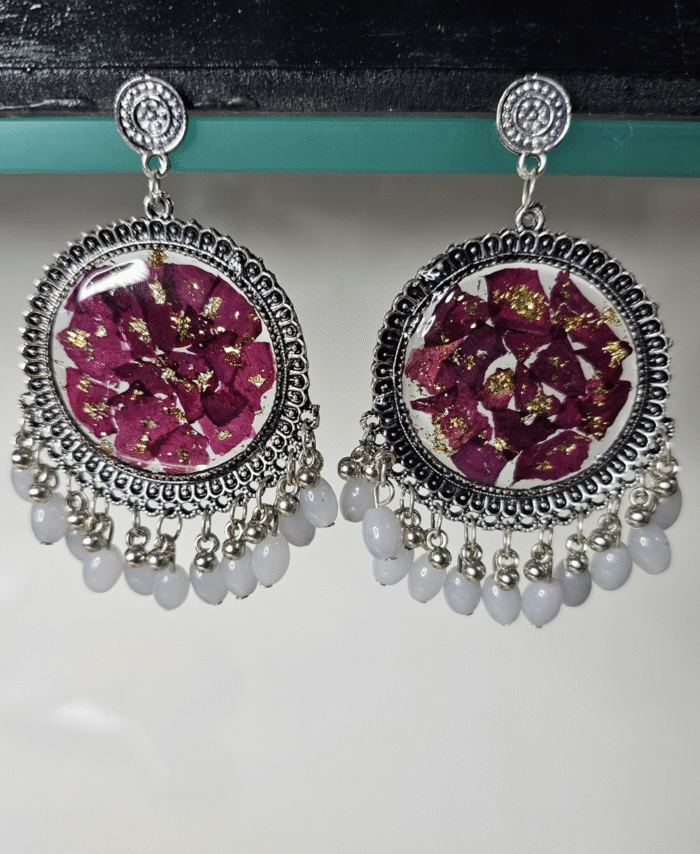 Purple resin earrings with floral petals and gold flakes.