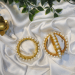 Handcrafted golden thread kada bangle with white pearls on satin background