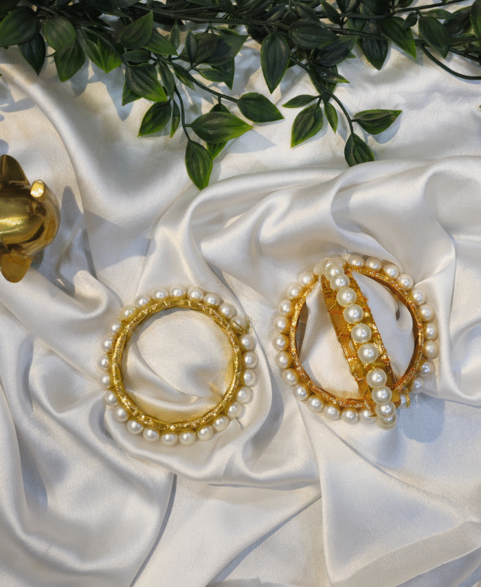 Handcrafted golden thread kada bangle with white pearls on satin background