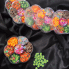 Flower-shaped wheel filled with colourful Fimo fruit and decorative clay slices for resin and nail art.