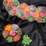 Flower-shaped wheel filled with colourful Fimo fruit and decorative clay slices for resin and nail art.