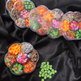Flower-shaped wheel filled with colourful Fimo fruit and decorative clay slices for resin and nail art.