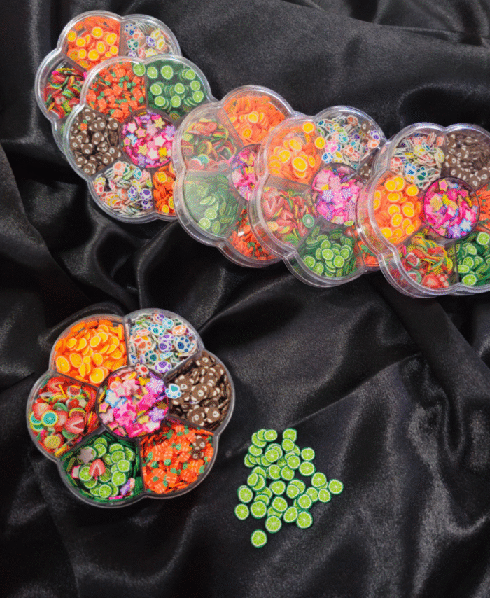 Flower-shaped wheel filled with colourful Fimo fruit and decorative clay slices for resin and nail art.