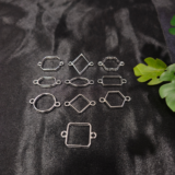 Silver-plated assorted resin bezels in multiple shapes are displayed on a black background. Mixed-shape silver bezels with double hooks arranged neatly for resin jewellery making.