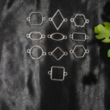 Silver-plated assorted resin bezels in multiple shapes are displayed on a black background. Mixed-shape silver bezels with double hooks arranged neatly for resin jewellery making.