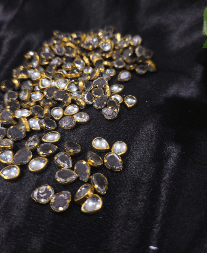 Gold-framed pear Kaudan stones scattered on black fabric