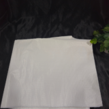 “White disposable waterproof apron sheet placed on black fabric background”