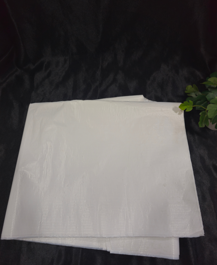 “White disposable waterproof apron sheet placed on black fabric background”