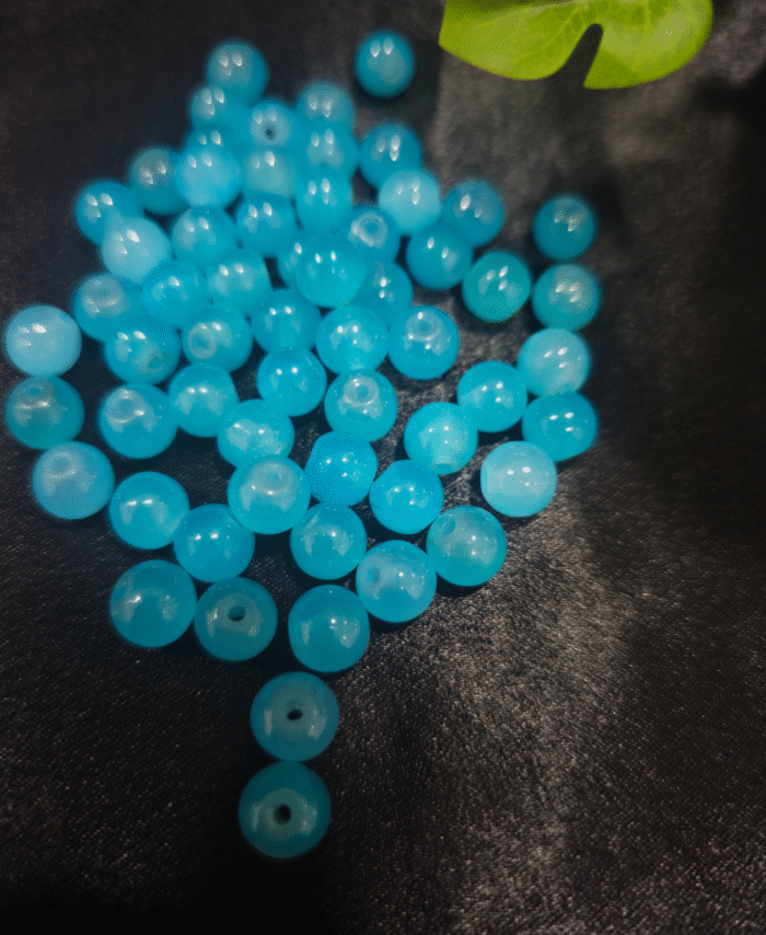 Clear faceted crystals are scattered on black fabric, with a green leaf visible in the corner.