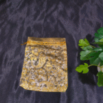 Golden floral organza drawstring gift bag placed on black fabric background”