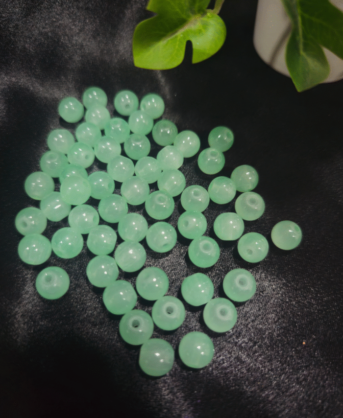 Clear faceted crystals are scattered on black fabric, with a green leaf visible in the corner.