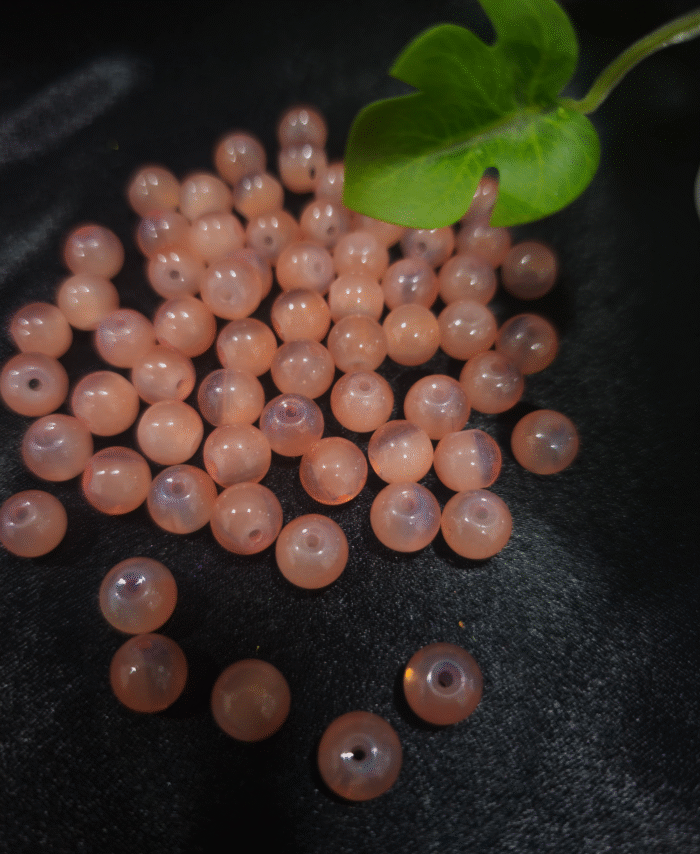 Clear faceted crystals are scattered on black fabric, with a green leaf visible in the corner.
