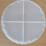 Round silicone coaster mould divided into four equal pizza slices on a wooden surface. Pizza slice resin coaster mould with wavy edge design