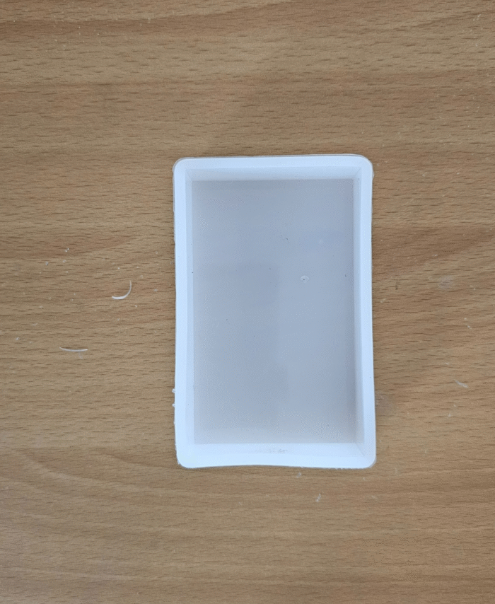Deep rectangular silicone mould for rose preservation White flexible resin mould for flower casting on a wooden surface