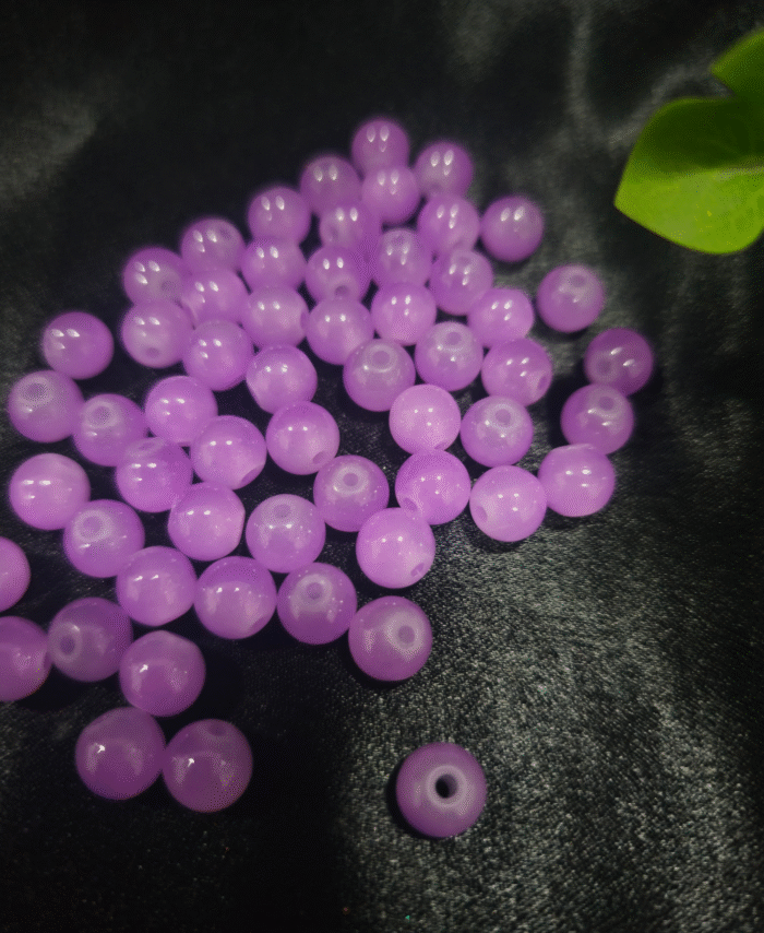 Clear faceted crystals are scattered on black fabric, with a green leaf visible in the corner.
