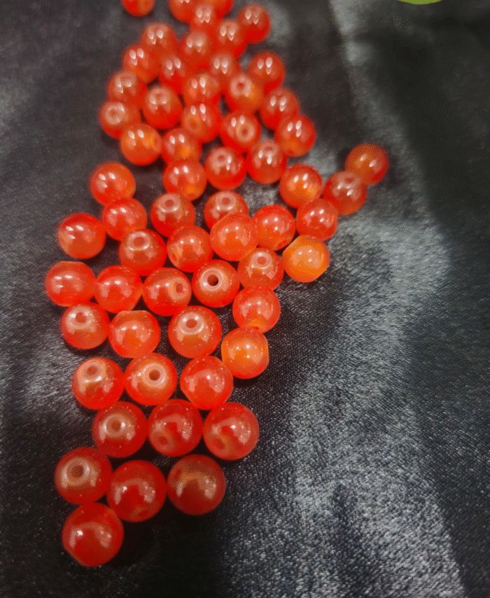 Clear faceted crystals are scattered on black fabric, with a green leaf visible in the corner.