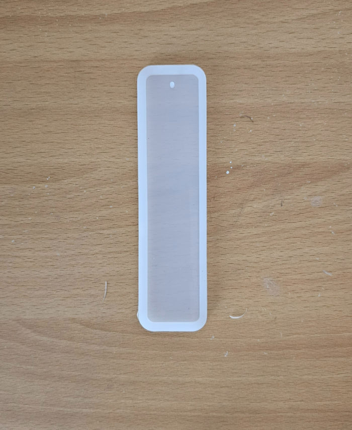 Three transparent silicone bookmark moulds in small, medium, and large sizes on a wooden surface 3-in-1 bookmark mould set with hole for tassels