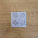 White plastic tray with four 1-inch circular cavities for crafting pop sockets, placed on a wooden surface.