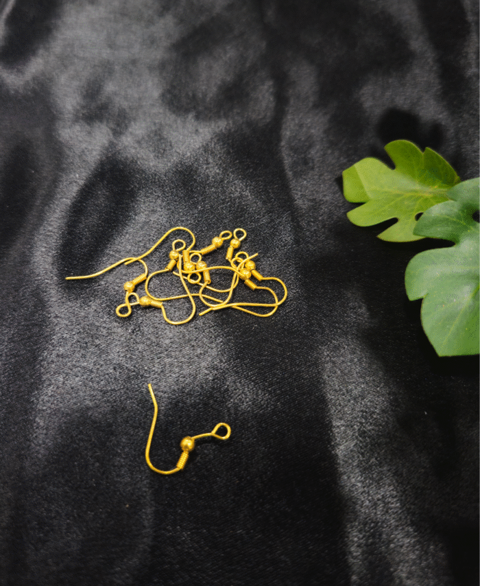 Gold earring hooks for jewellery making placed on black fabric.