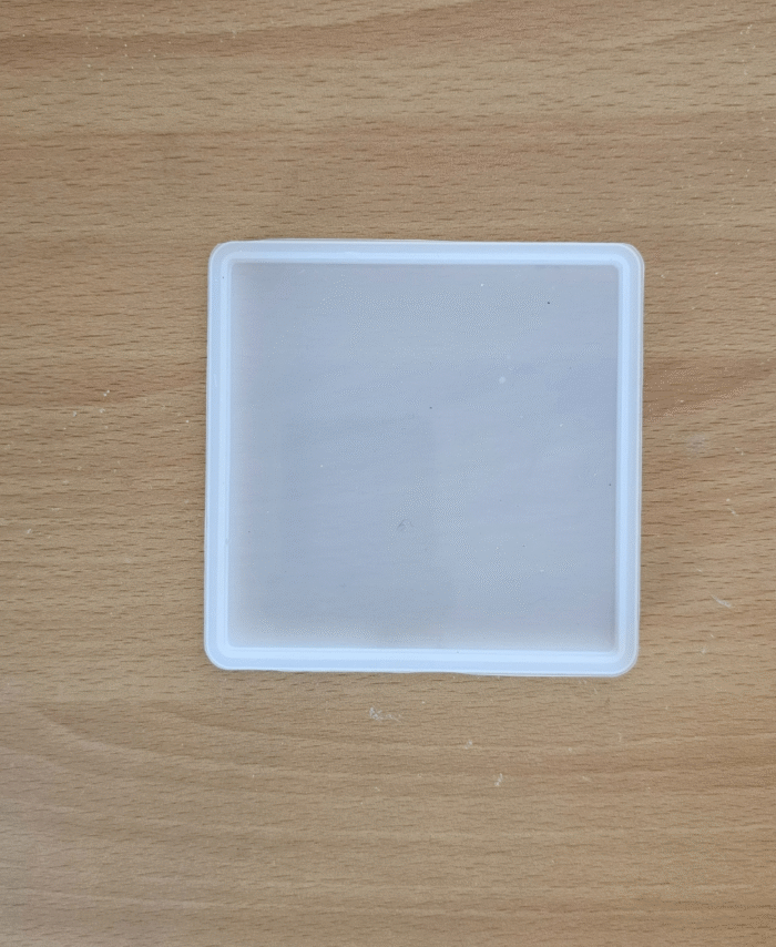 4-inch square silicone mould for resin casting placed on a wooden background.