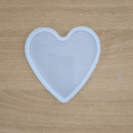 Translucent heart-shaped coaster with smooth finish, placed on a wooden surface.