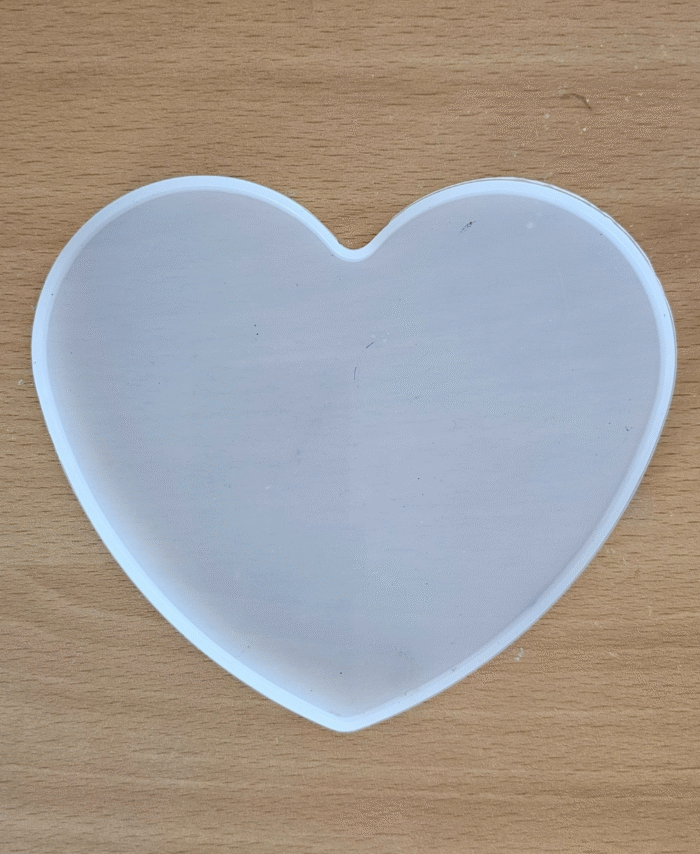 Translucent heart-shaped coaster with smooth finish, placed on a wooden surface.