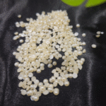 Small ivory flatback pearls in assorted sizes are scattered on black velvet fabric.