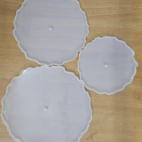 "Three silicone wavy-edge cake stand moulds in different sizes placed on a wooden surface"