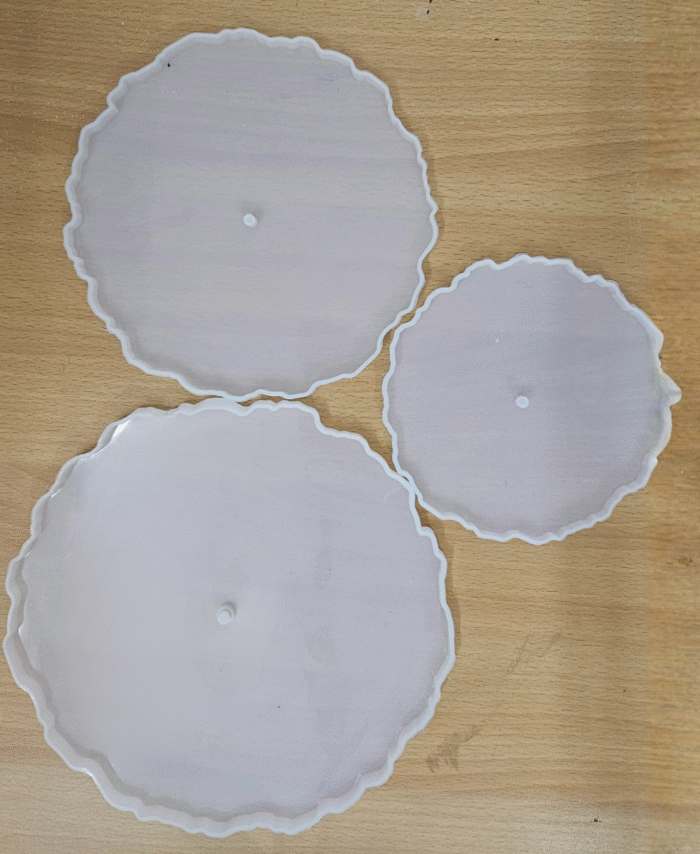 "Three silicone wavy-edge cake stand moulds in different sizes placed on a wooden surface"