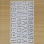 Transparent silicone alphabet mould containing A–Z letters with keychain holes placed on a wooden surface
