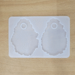 “Silicone mould with two agate-shaped makeup palette cavities placed on a wooden surface.”