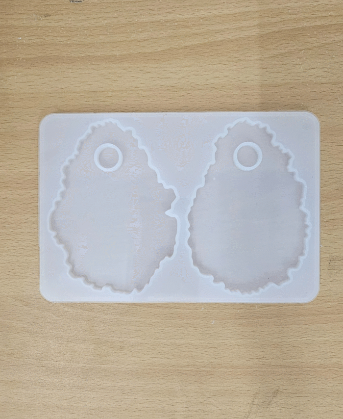 “Silicone mould with two agate-shaped makeup palette cavities placed on a wooden surface.”