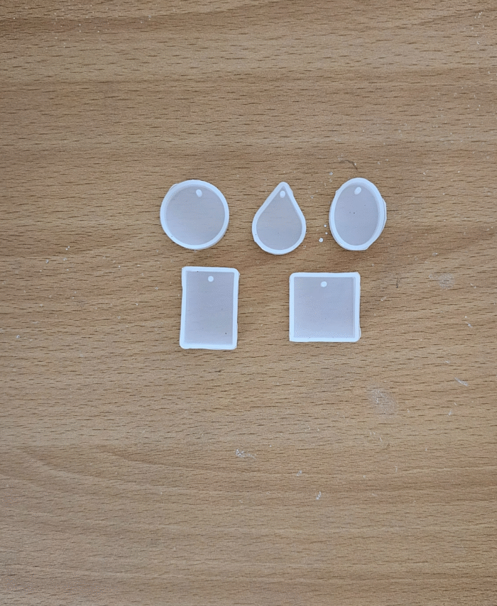 Silicone pendant mould set with round, oval, teardrop, and rectangular shapes placed on a wooden background