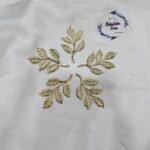 Gold metal leaf branch charm with detailed textured leaves placed on a white background.