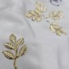 Gold metal leaf branch charm with detailed textured leaves placed on a white background.