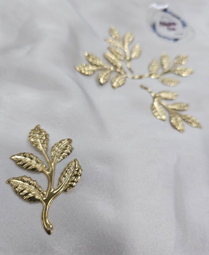 Gold metal leaf branch charm with detailed textured leaves placed on a white background.