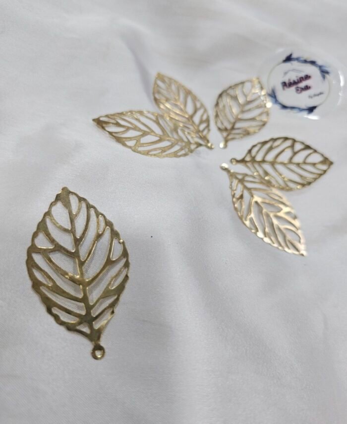Gold filigree leaf metal charms arranged in a circular pattern on a white background.