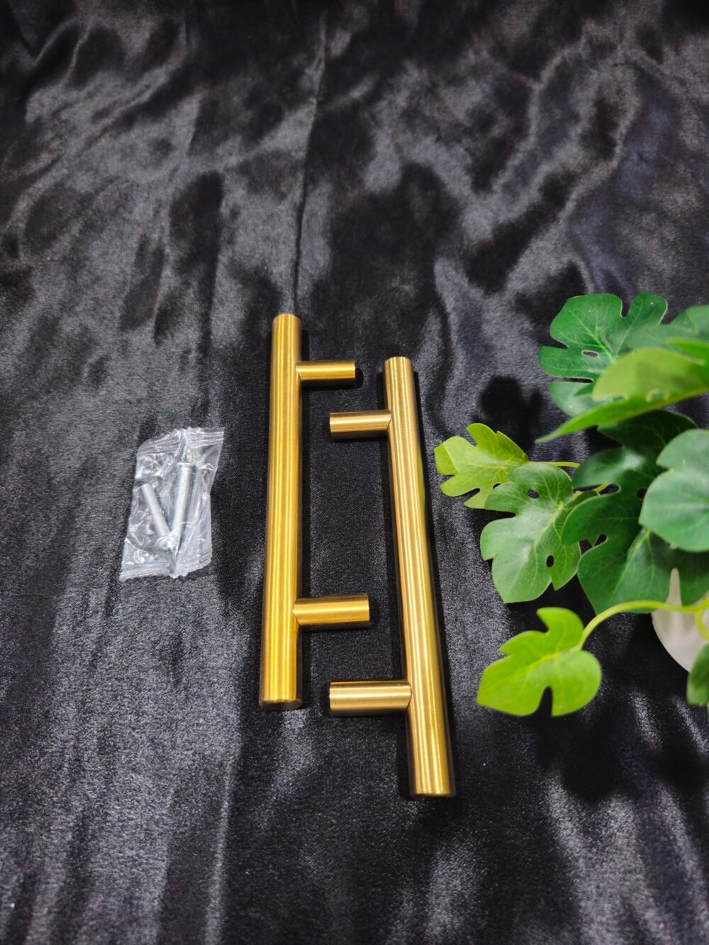 Gold 6 inch tray handle with screws placed on a black fabric background