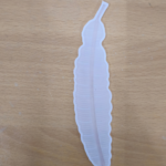 Feather-shaped bookmark with a delicate and elegant design placed on a surface.