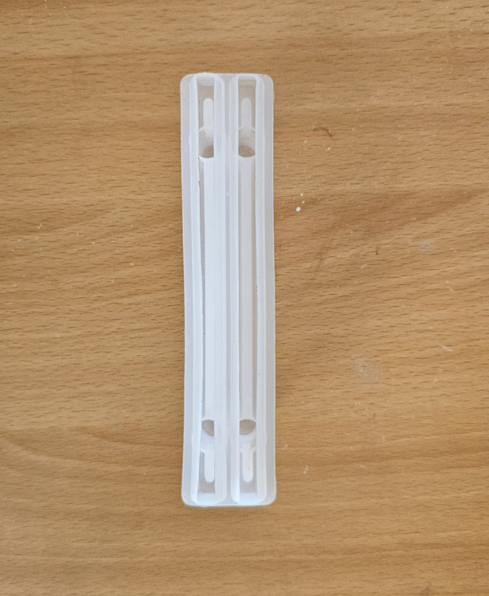Transparent silicone mould with two long, narrow cavities for casting resin tray handle pieces placed on a wooden background.
