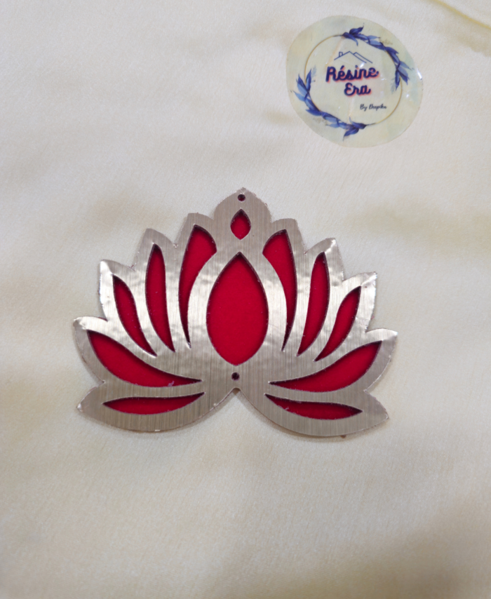 A Red and metallic acrylic lotus-shaped décor piece placed on a soft fabric background.