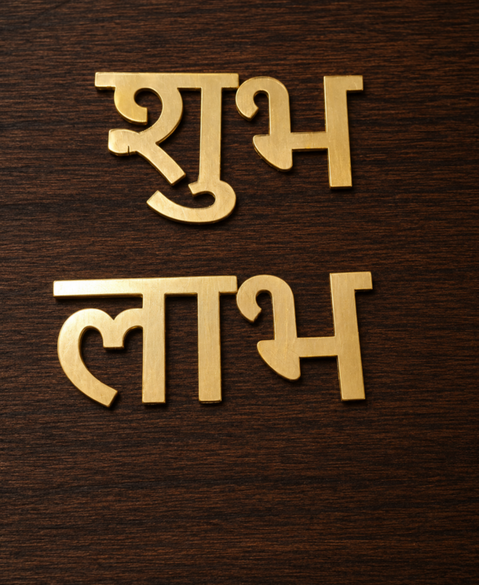 Golden acrylic Subha Labh Hindi words placed on shiny blue fabric background.