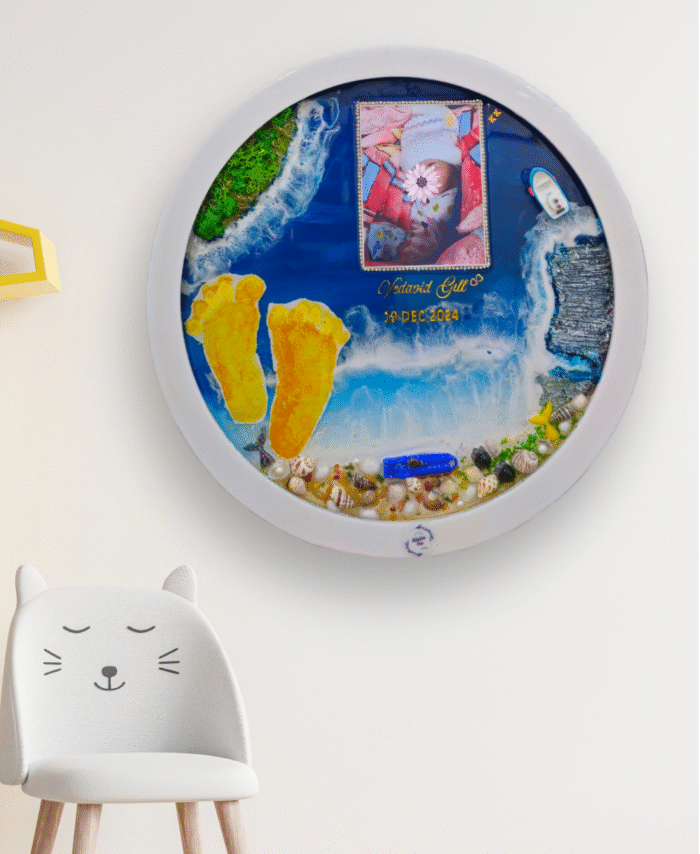 Round ocean-themed resin wall art with baby footprints, photo frame, seashell decorations, and LED light, displayed on a white wall.