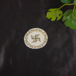 Small golden sticker placed on a black background with green leaves in the top right corner.