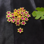 Gold-tone flower-shaped kundan stone beads with pink centre stones on a black background.