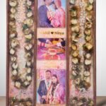 3-column full varmala preservation frame with preserved wedding garland flowers, couple photos, pearls, and decorative elements set in epoxy resin wooden wall frame.