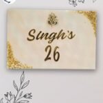 Elegant resin nameplate with family name and house number in gold finish on marble-style background