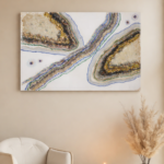 Neutral geode wall art with gold, blue, and green accents displayed on a beige wall above a modern chair and candles
